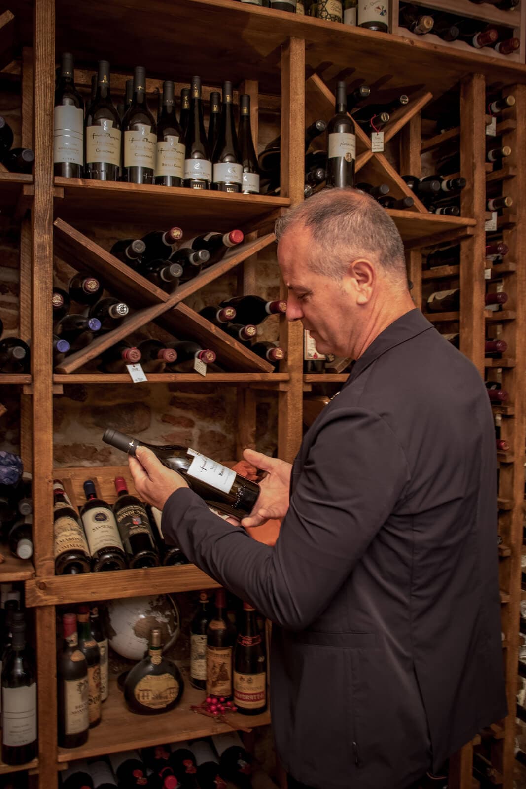 Mario mostra una bottiglia pregiata nella cantina del Ristorante Cian